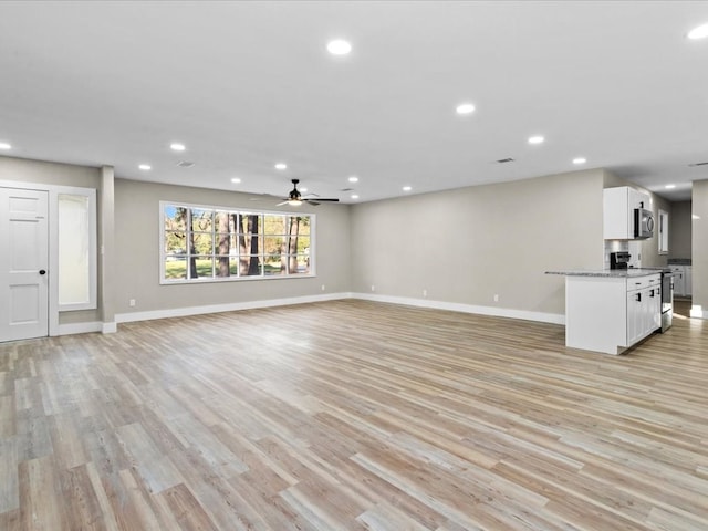 unfurnished living room featuring ceiling fan and light hardwood / wood-style flooring