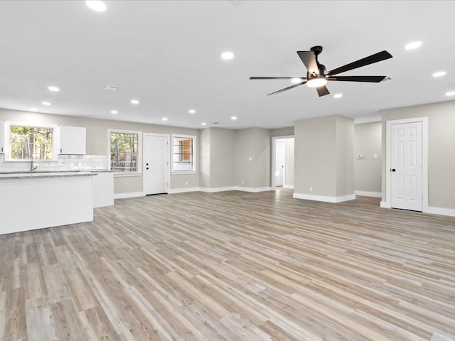 unfurnished living room featuring ceiling fan, sink, and light hardwood / wood-style flooring