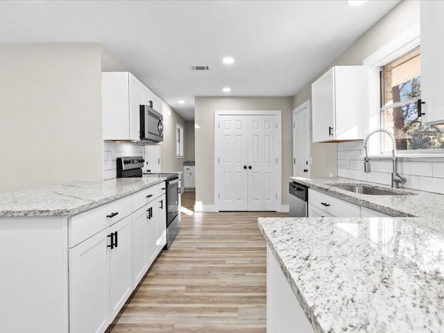 kitchen with appliances with stainless steel finishes, tasteful backsplash, light stone counters, sink, and white cabinets