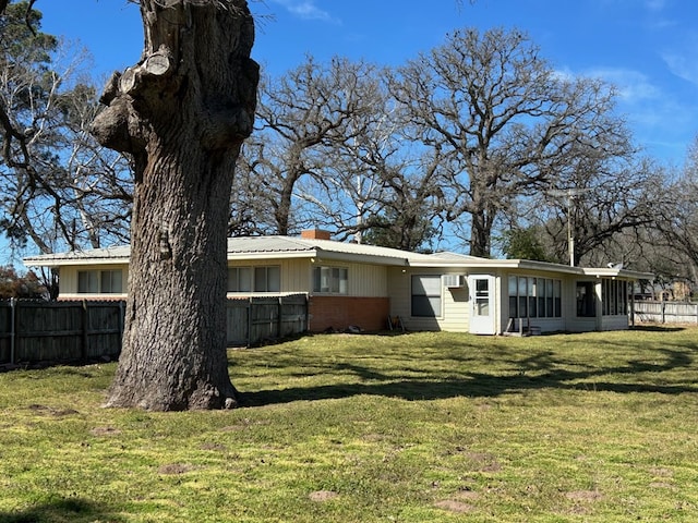 back of house featuring brick siding, a lawn, a chimney, and fence