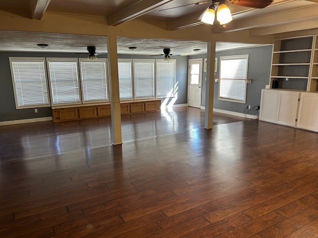 spare room with ceiling fan, beam ceiling, baseboards, and dark wood-style flooring