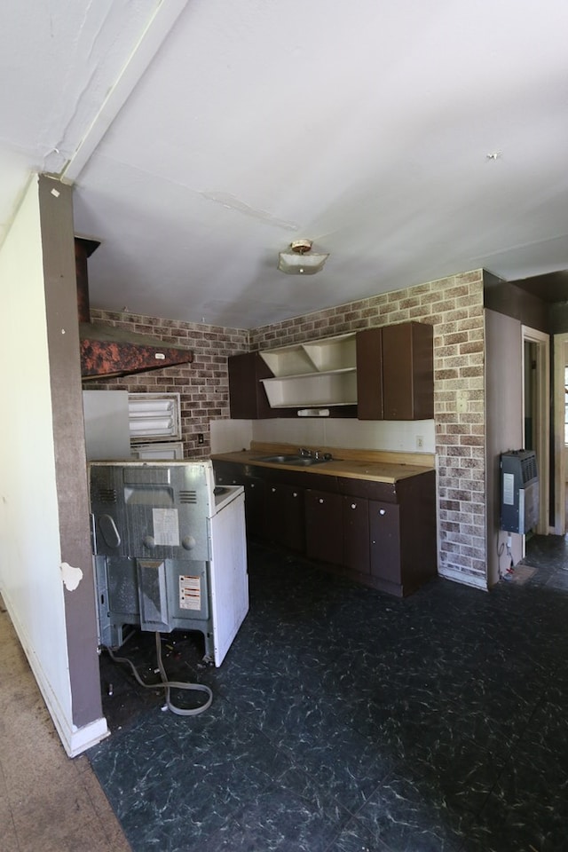 kitchen with heating unit, dark brown cabinets, beamed ceiling, and sink