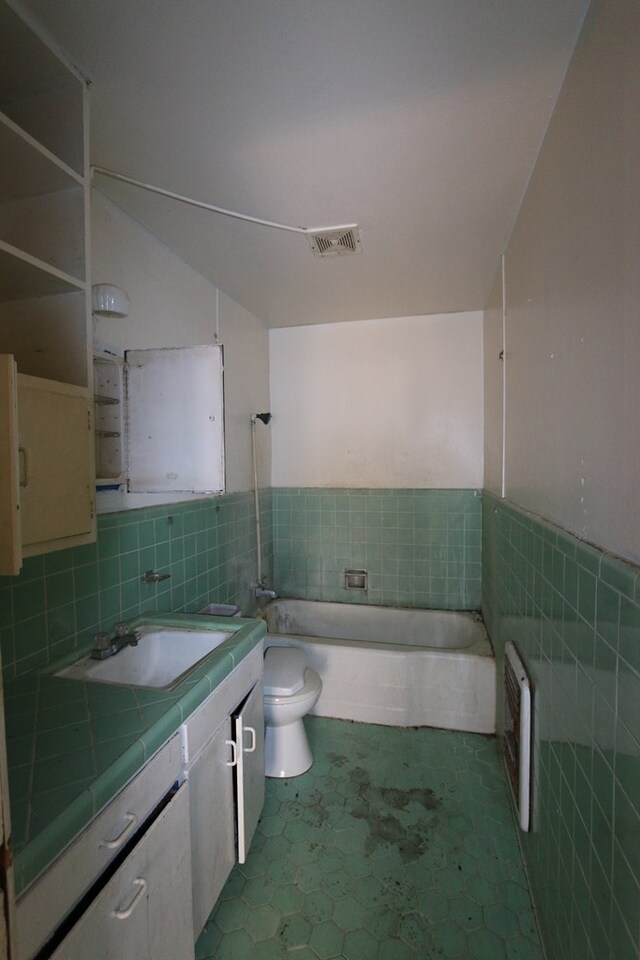 bathroom featuring vanity, tile patterned floors, toilet, tile walls, and a tub