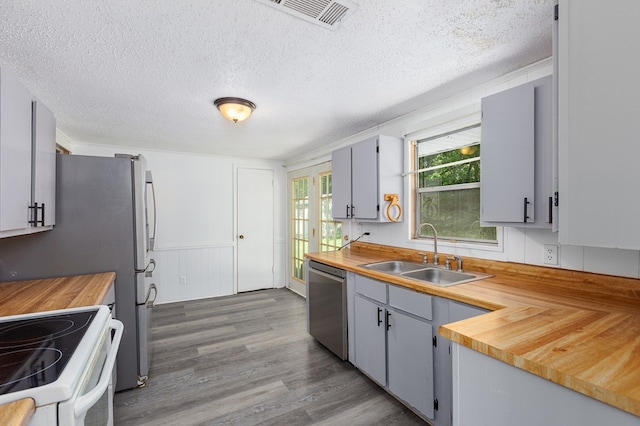 kitchen with electric range, butcher block counters, wood finished floors, dishwasher, and a sink