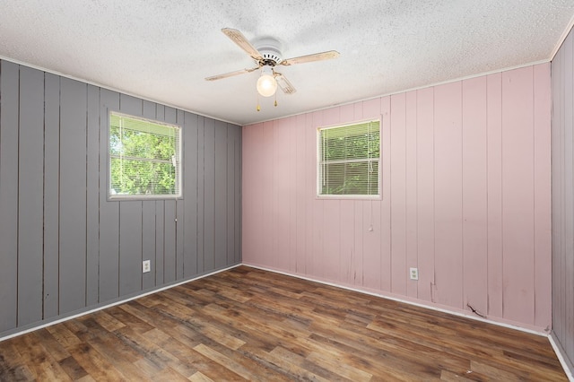 spare room with ceiling fan, a textured ceiling, baseboards, and wood finished floors