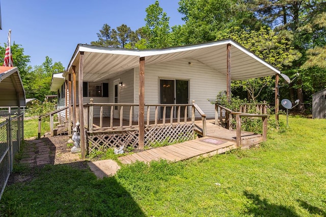 back of property with a wooden deck, fence, and a lawn
