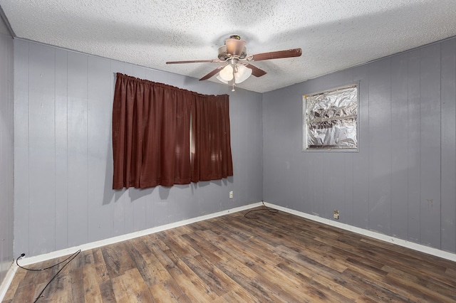 empty room with dark wood-type flooring, baseboards, a ceiling fan, and a textured ceiling
