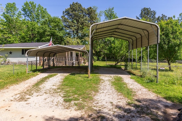 view of parking / parking lot featuring a carport, driveway, and fence