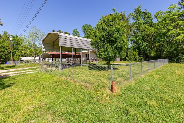 view of yard featuring driveway, a detached carport, and fence