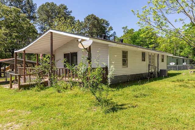 view of front of house featuring central air condition unit, fence, and a front lawn