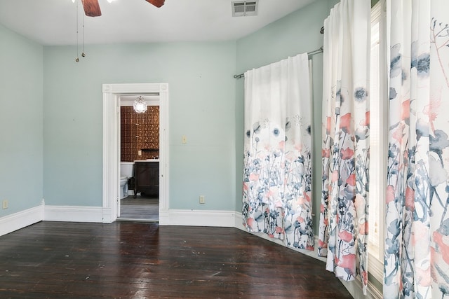 empty room with ceiling fan and dark hardwood / wood-style flooring