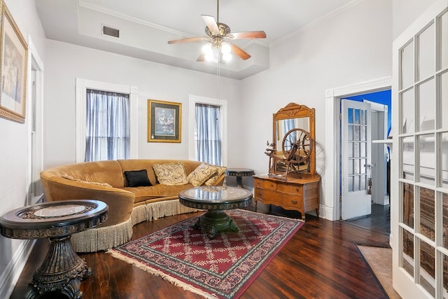 living room with dark hardwood / wood-style floors, ceiling fan, a raised ceiling, crown molding, and french doors