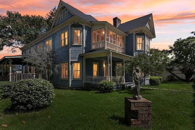 view of front of house with a yard, a sunroom, and a porch