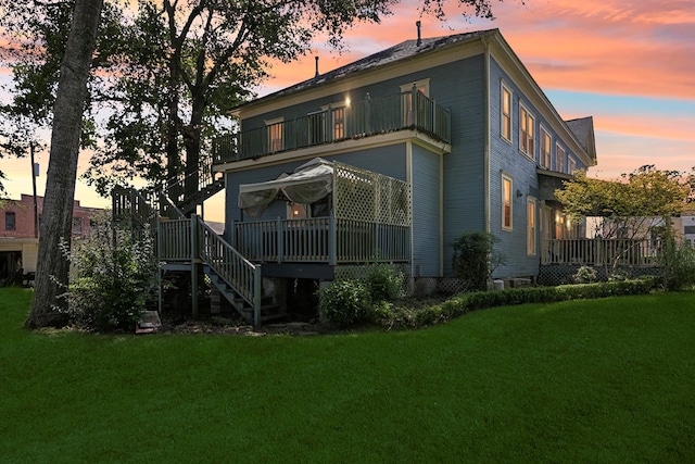 back house at dusk featuring a lawn