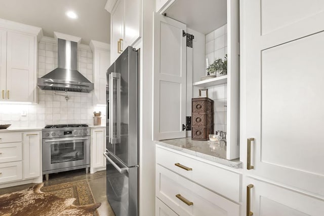 kitchen featuring white cabinets, backsplash, high end appliances, and wall chimney range hood