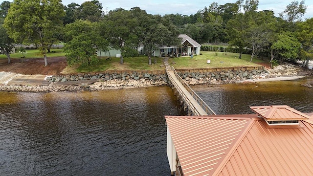 view of dock with a lawn and a water view