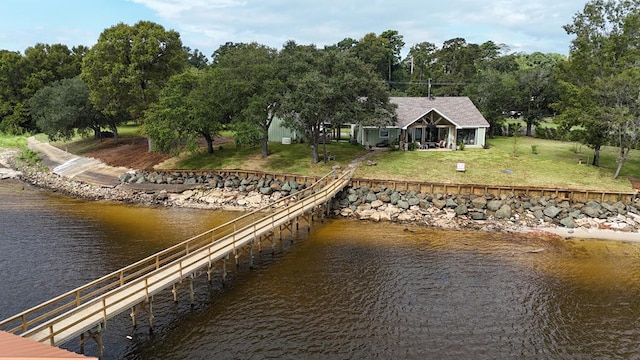 view of dock with a yard and a water view