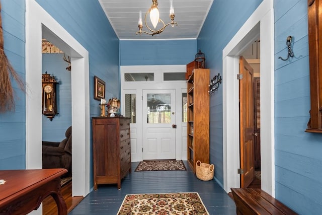 doorway to outside featuring wood walls, dark hardwood / wood-style floors, and an inviting chandelier