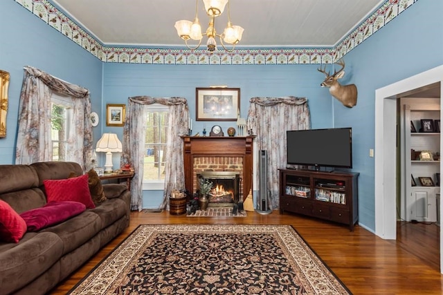 living room featuring a fireplace, ornamental molding, hardwood / wood-style flooring, and a notable chandelier