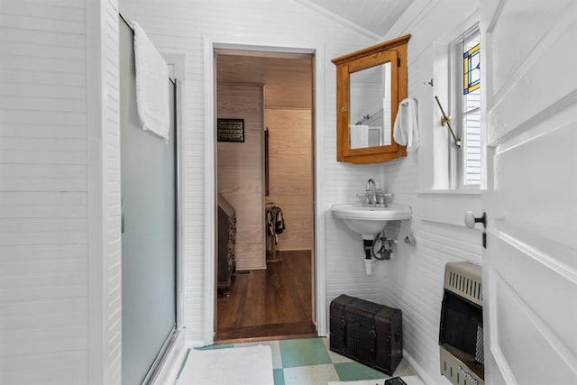 bathroom with crown molding, sink, wooden walls, a shower with shower door, and heating unit