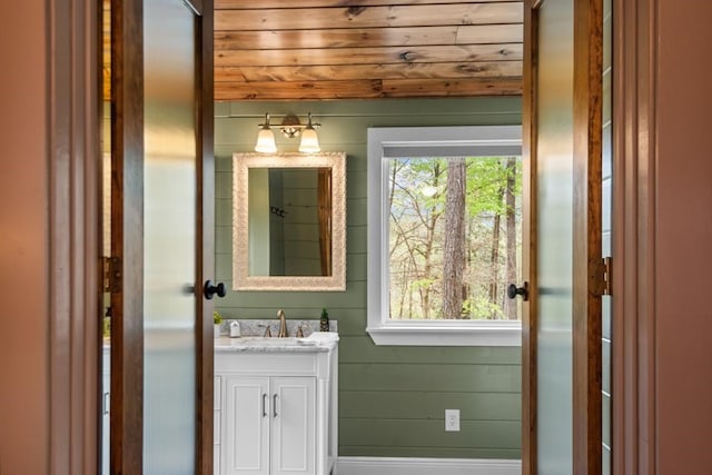 bathroom featuring vanity, wooden walls, and wooden ceiling