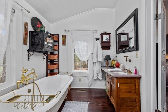 bathroom with a tub to relax in, hardwood / wood-style floors, vanity, and vaulted ceiling