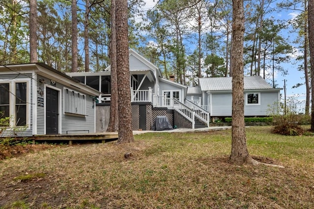 rear view of house with a yard, a wooden deck, and a sunroom