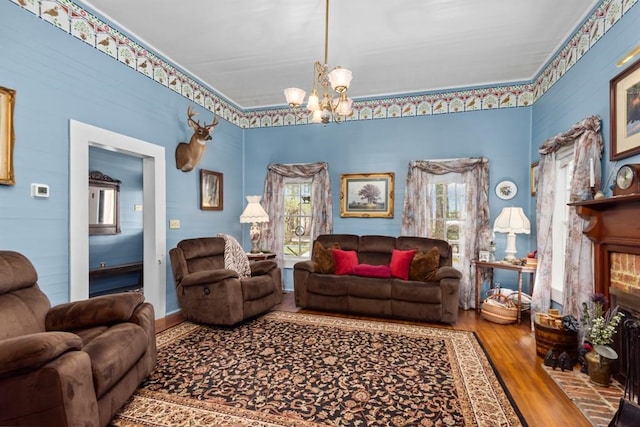 living room featuring hardwood / wood-style flooring, plenty of natural light, a brick fireplace, and a notable chandelier