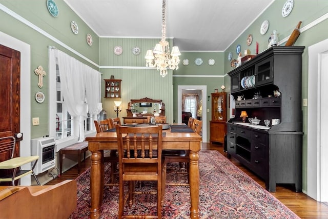 dining room featuring hardwood / wood-style floors, heating unit, an inviting chandelier, and crown molding