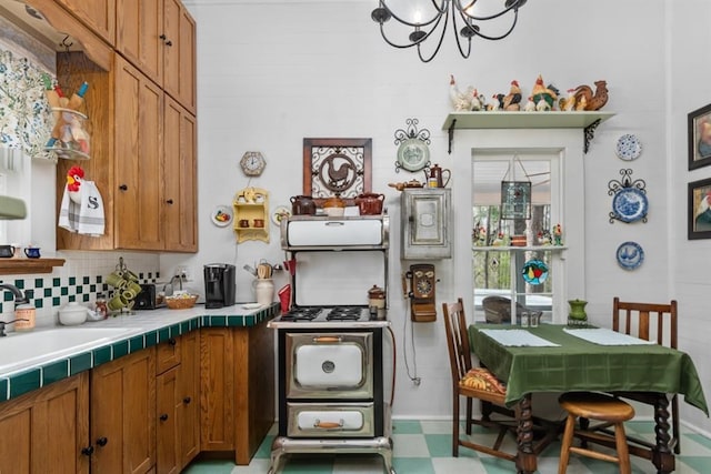 kitchen featuring backsplash, tile counters, sink, and a notable chandelier