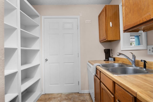 kitchen with sink, white dishwasher, and a textured ceiling