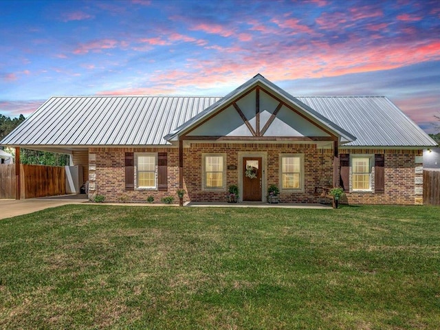view of front of house featuring metal roof, a front yard, an attached carport, and fence