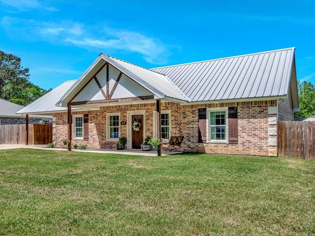 view of front facade with fence, metal roof, brick siding, and a front lawn