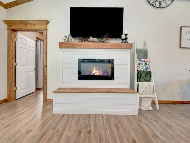 unfurnished living room featuring baseboards, wood finished floors, and a glass covered fireplace
