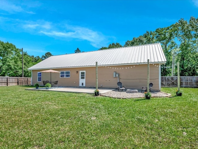 back of property with metal roof, a lawn, and a patio area