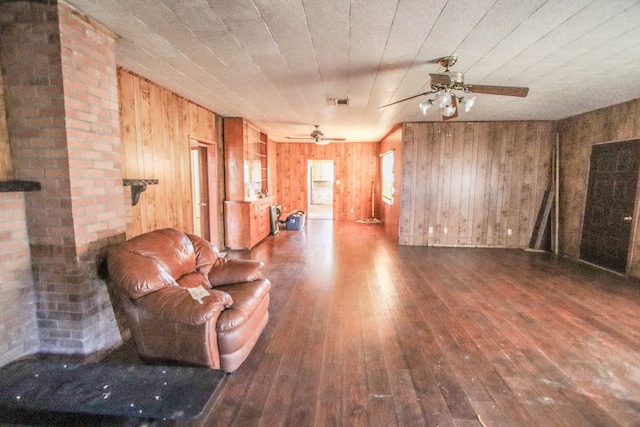 unfurnished living room with hardwood / wood-style flooring, a ceiling fan, and wood walls