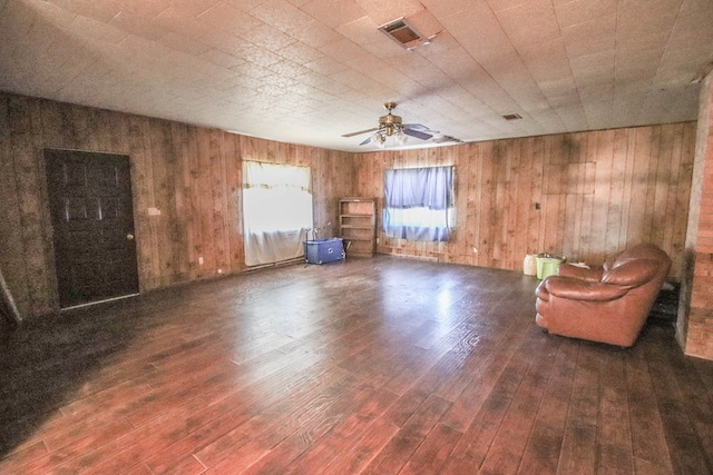 unfurnished room featuring ceiling fan, dark hardwood / wood-style floors, and wooden walls