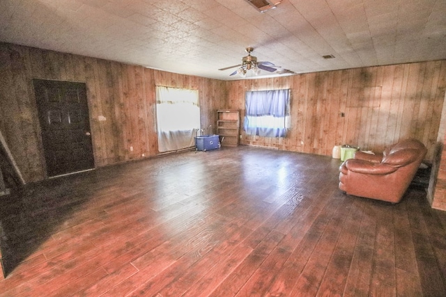 unfurnished room with ceiling fan, dark wood-type flooring, and wooden walls