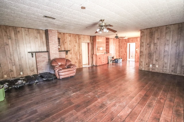 unfurnished living room with ceiling fan, dark hardwood / wood-style flooring, and wooden walls