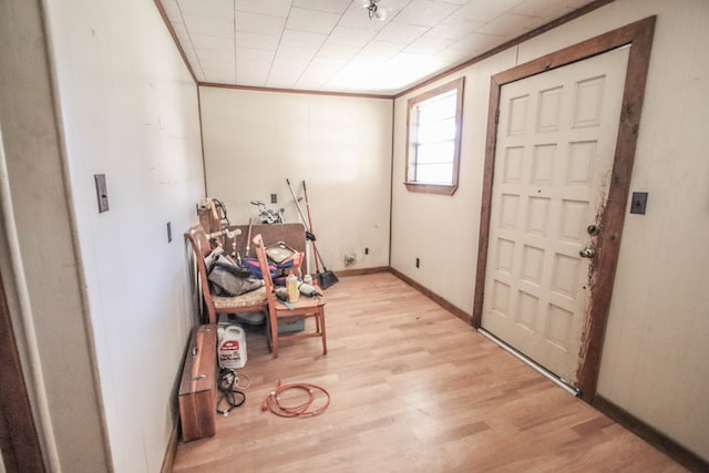 foyer entrance featuring baseboards, light wood-style floors, and ornamental molding