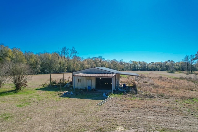 view of outdoor structure with a rural view, a carport, and a yard