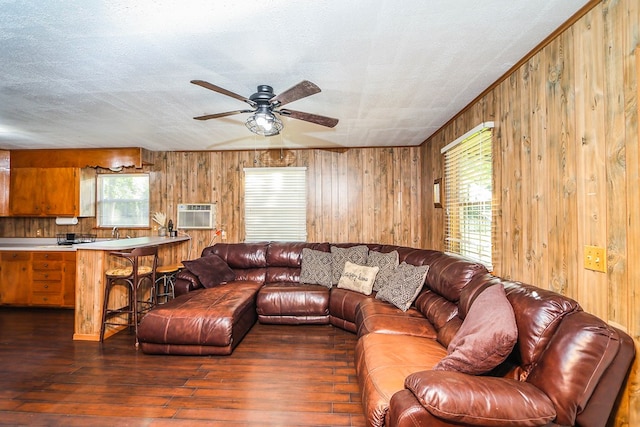 496 County Road 486, Broaddus, TX 75929 - living room with wooden walls, ceiling fan, dark wood-type flooring, a wall mounted air conditioner, and a textured ceiling