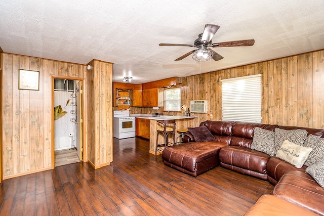 496 County Road 486, Broaddus, TX 75929 - living area with wooden walls, ceiling fan, dark wood-type flooring, a textured ceiling, and a wall mounted air conditioner
