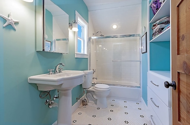 bathroom featuring shower / bath combination with glass door, tile patterned floors, and toilet