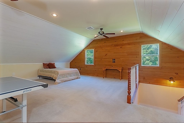 unfurnished bedroom featuring carpet flooring, ceiling fan, lofted ceiling, and wooden walls