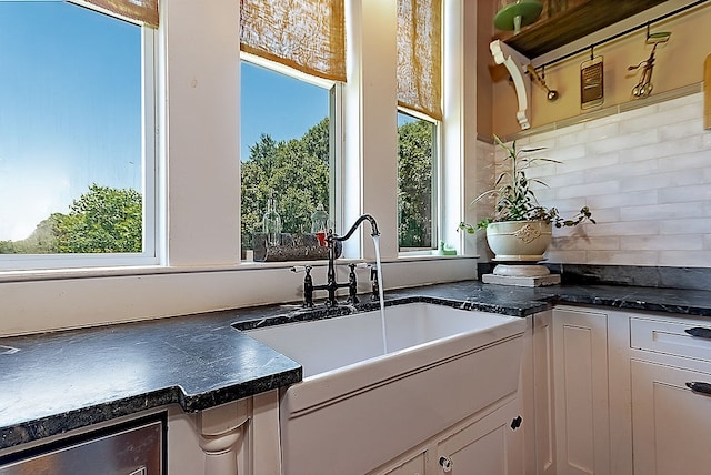 kitchen with backsplash, white cabinetry, plenty of natural light, and sink