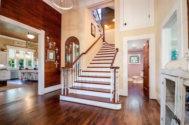 stairway with wood-type flooring, a towering ceiling, and wood walls