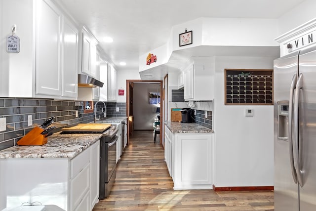 kitchen with light stone counters, white cabinets, range with electric stovetop, and stainless steel refrigerator with ice dispenser