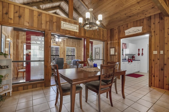 dining area featuring light tile patterned floors, wood ceiling, wooden walls, and beamed ceiling