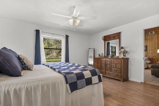 bedroom with visible vents, a textured ceiling, wood finished floors, and crown molding